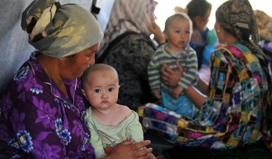 Ethnic Uzbek  women cared for their children under a tent by the Kyrgyzstan-Uzbekistan  border yesterday. Nearly half of the southern Kyrgyzstan’s roughly  800,000 Uzbeks fled the area.