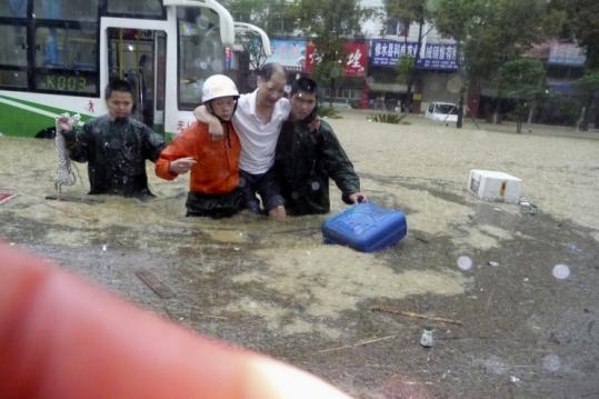 Firefighters carried  a man trapped in the floods yesterday in Xiushui, in central China’s  Jiangxi province.