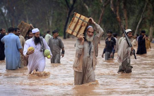 Residents waded through the streets yesterday in Peshawar, Pakistan, after the rain washed away roads and submerged houses.