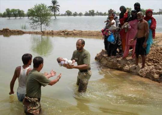 Pakistani army soldiers passed a baby to safety as they helped people flee from their flooded village yesterday. More than 27,000 people were reported to be trapped by the floods.
