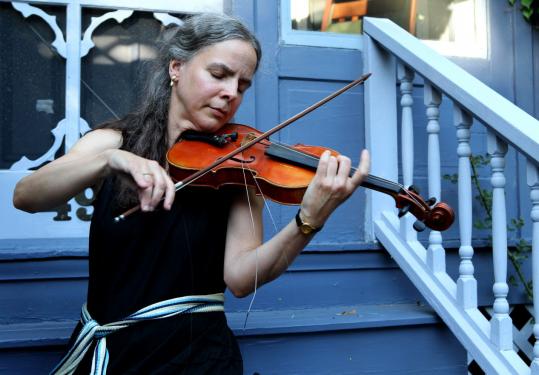 Valerie Rose Taylor played her reclaimed violin outside her home in Watertown. The Berklee College of Music professor had left the instrument behind on a bus after a long journey.