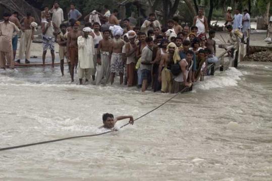 A man crossed a swollen canal yesterday after a bridge was washed away in Ghazi Gat, in central Pakistan. Flooding in the nation over the past two weeks has claimed 1,500 lives.