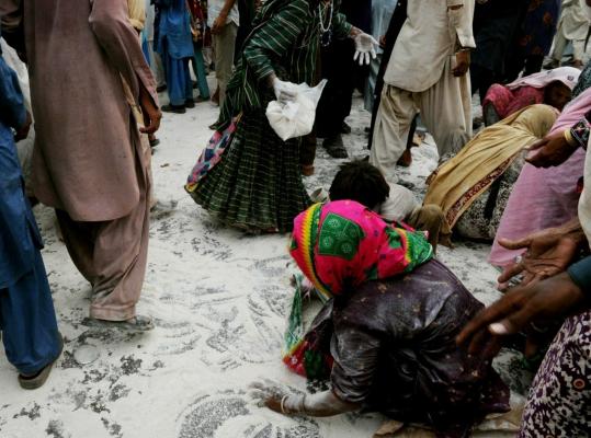 Pakistanis displaced by floods collected wheat flour from the road at a distribution point near the southern coast yesterday. Relief workers say they have reached more than 2 million people.