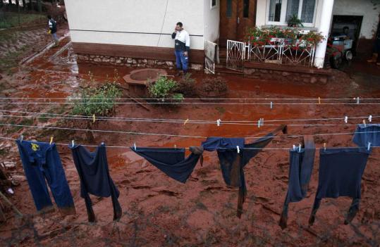 A resident surrounded by toxic red sludge used his phone in Kolontar, Hungary, after a factory’s reservoir burst its banks.
