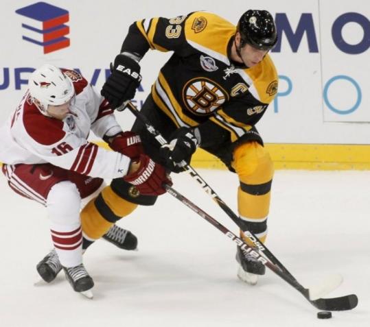 Bruins captain Zdeno Chara (right), fresh off a contract extension, tangles with Phoenix’s Petr Prucha in yesterday’s opener.