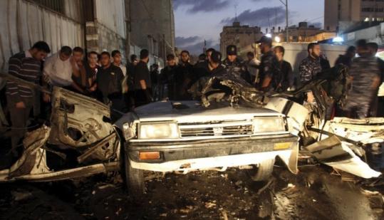 Palestinians gathered around a car destroyed in a Gaza street yesterday during an Israeli airstrike. Two people were killed and three people wounded in the strike.