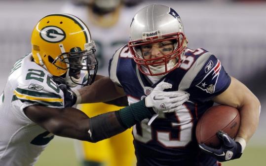 Wes Welker is tackled by Green Bay’s Charlie Peprah after one of his three catches Sunday night.