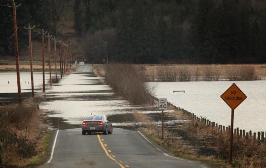 A flooded street northwest of Carnation, Wash., forced a driver to turn around on Sunday. Heavy rains and melting snow caused a Snoqualmie River tributary to overflow its banks.