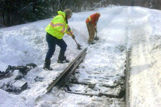 Mike Mazenkas (left) and Doug Oxner cleared snow last week from a switch on the MBTA’s commuter rail line in Walpole.