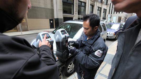 Tan Lee of the Boston Transportation Department scraped a decal off a Devonshire Street meter that is now equipped to accept credit card payments.