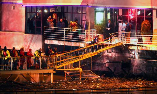 A woman walked down an improvised ramp, made of ladders and rope, from a barge in Covington, Ky., assisted by rescuers.