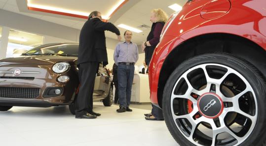 Angelo Falcone (center) of Acton and his wife, Rhonda, chatted with a salesman as they waited for the new Fiat at Kelly Fiat in Peabody.