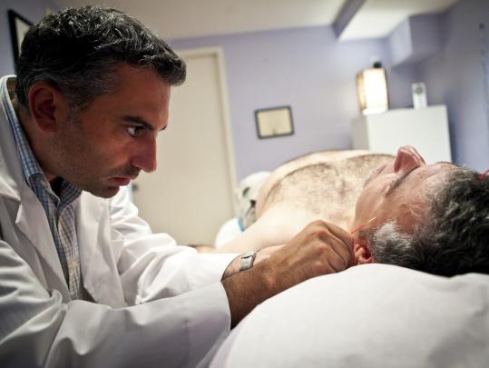 Robert Surabian performed holistic treatments for Geoff Ames, 52, of Salem, who suffers from migraines and aches and pains.