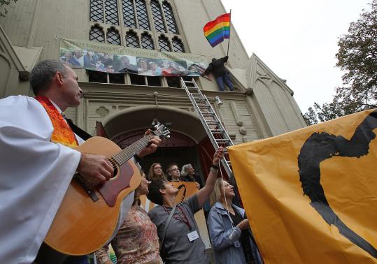 Members of First Parish Cambridge, Unitarian Universalist, raised a new rainbow flag to replace the one stolen two weeks ago. The Rev. Fred Smalls led the congregation in song.