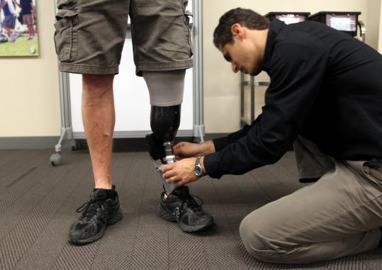 Michael Smerka, a clinical prosthetist, puts in battery into a BiOM worn by Rick Knapton, a full-time ankle test specialist.