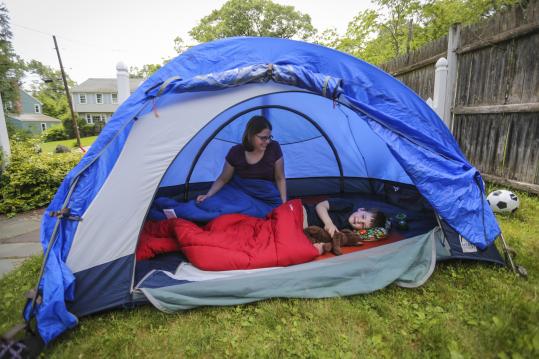 In Lexington, 5½-year-old Ian Robinson and his mother, Sue Paradis, test the family tent set up in their yard for Saturday’s campout.